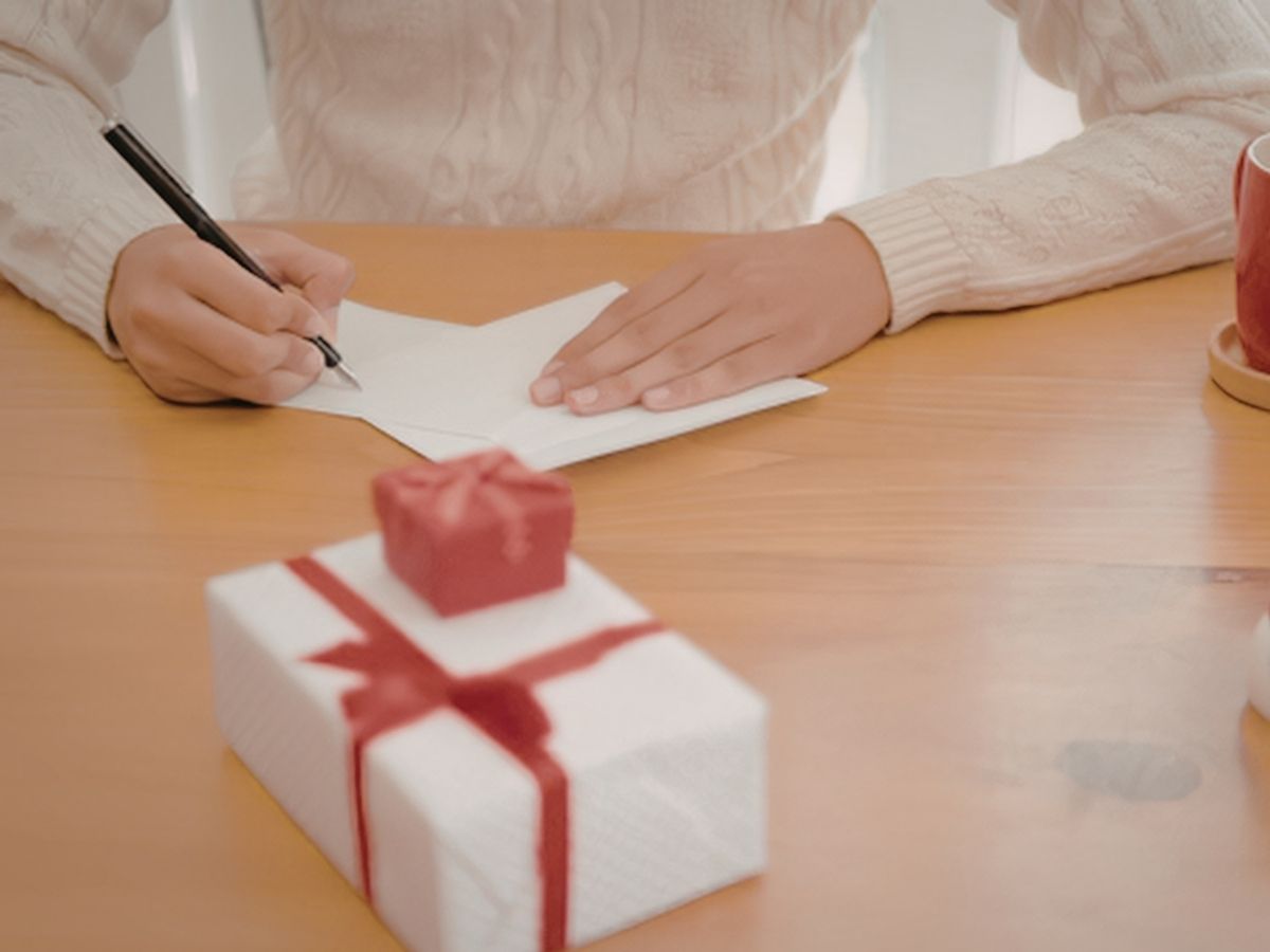 Seorang wanita menulis kartu ucapan untuk ditaruh di kado wisuda