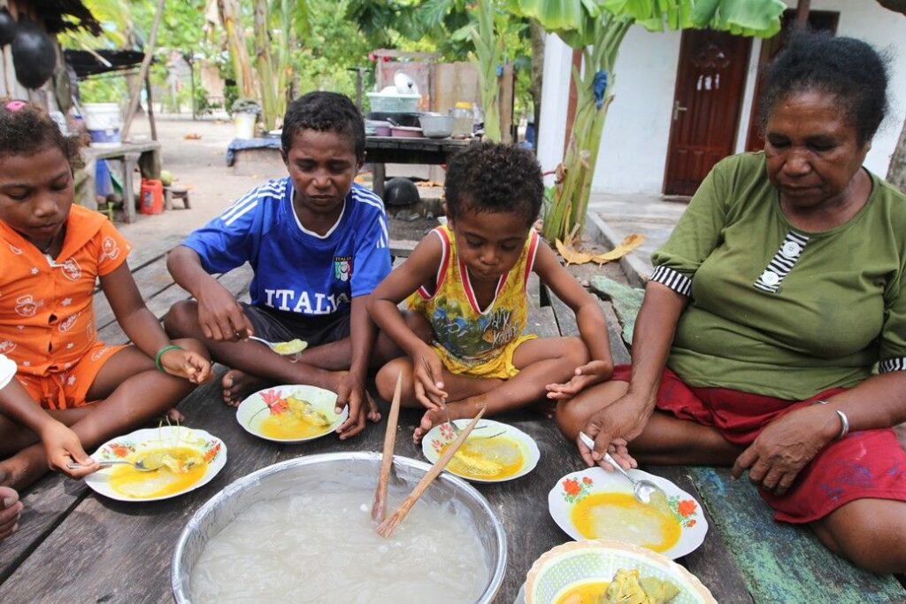 Keluarga Papua menikmati papeda sebagai makanan pokok tradisional Indonesia Timur